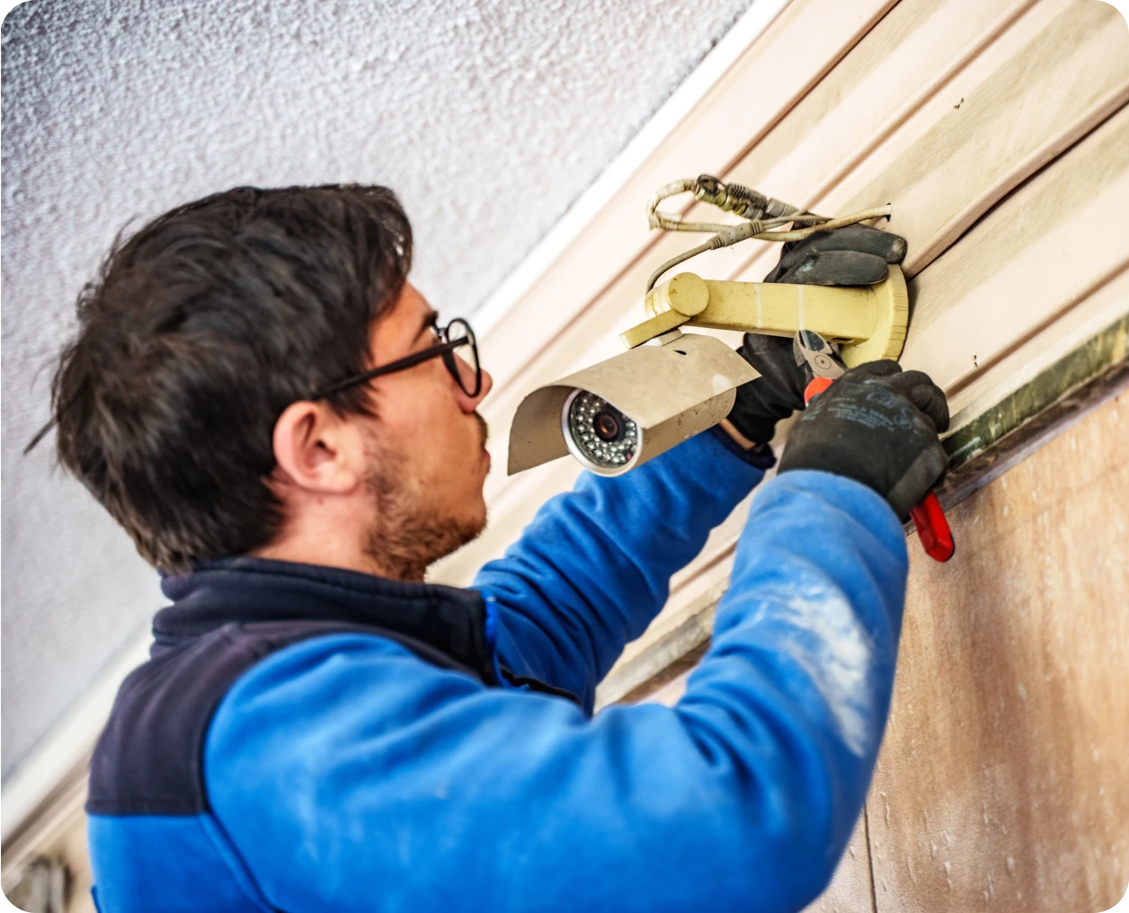 Man in blue jacket fixing surveillance device
